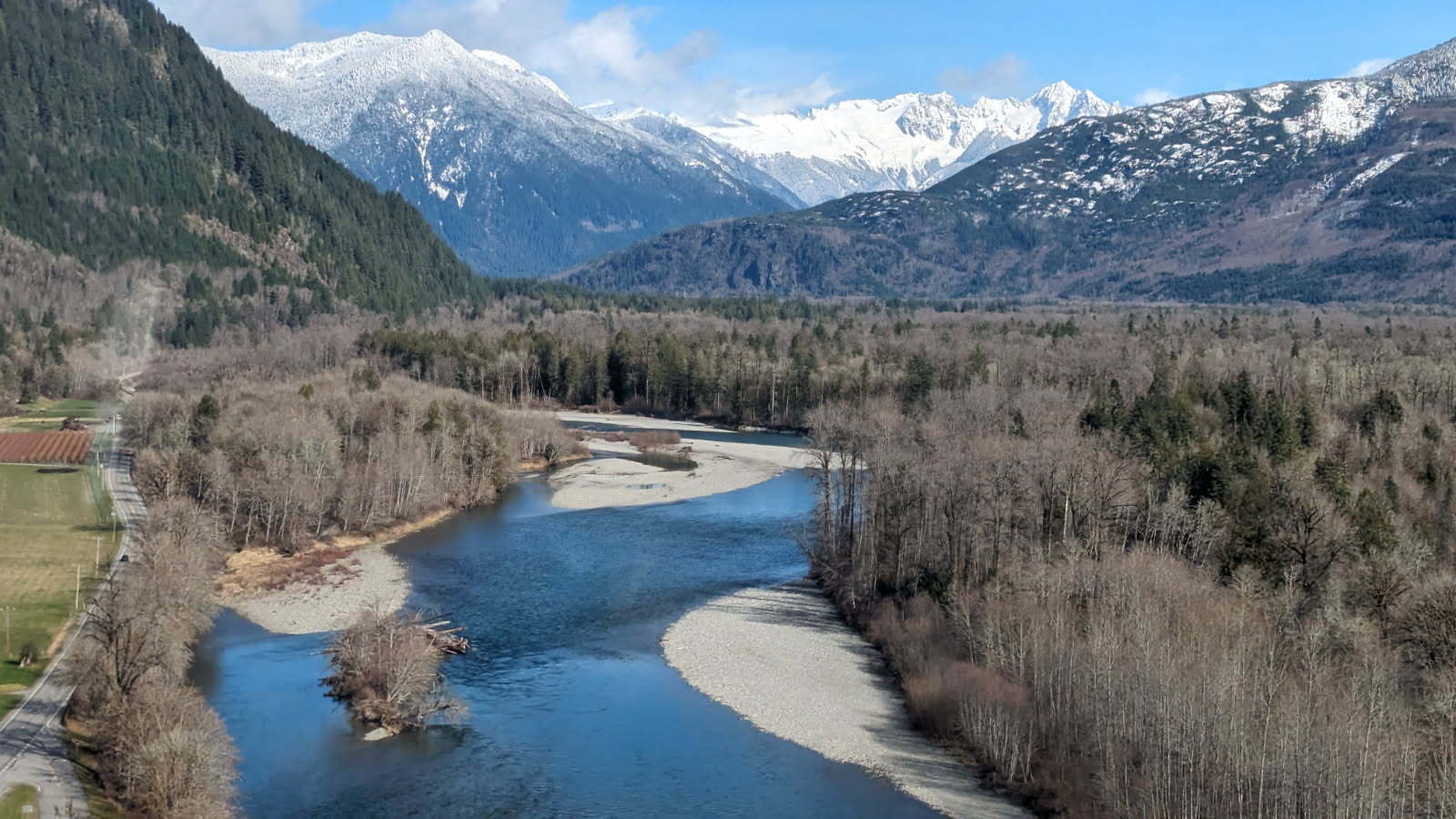 Aerial view of Skagit River in winter. The mountains and hills in the background are capped with snow.